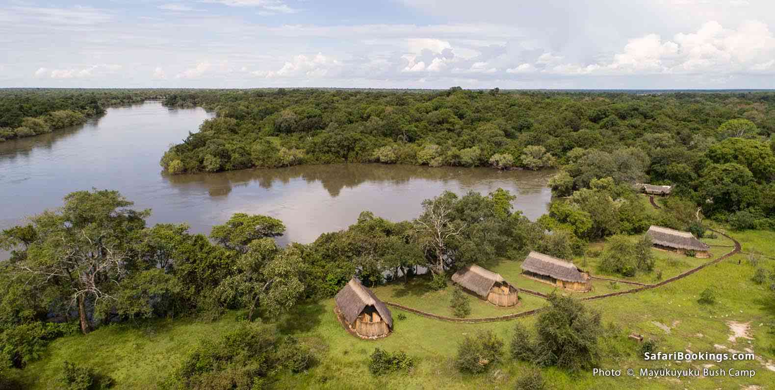 Four thatch-shaded tents facing the river