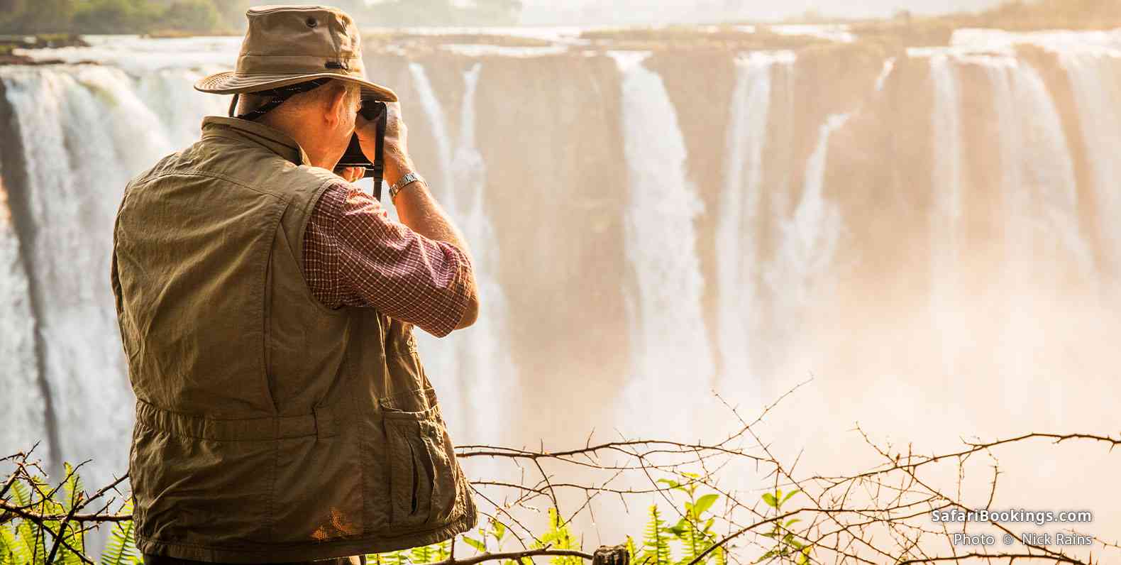 A photographer captures the sunrise over Victoria Falls' Main Falls (Zimbabwe) during the Dry season
