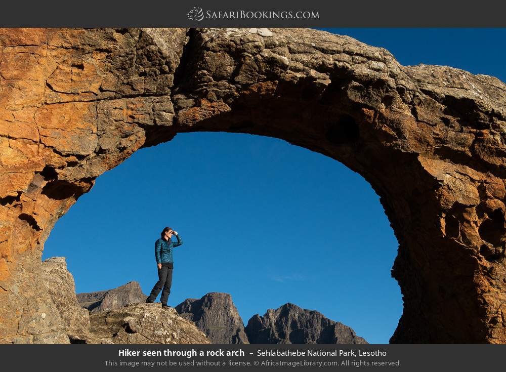 Hiker seen through a rock arch, Sehlabathebe NP in Sehlabathebe National Park, Lesotho