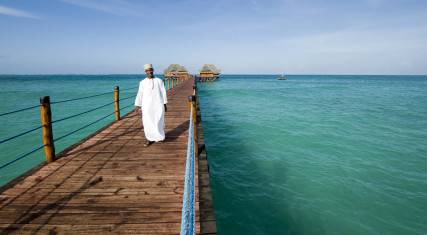 Waiter walking on a jetty leading to a beach bar